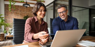 Business,Team,Of,Two,Executives,Working,Together,Using,Laptop,In