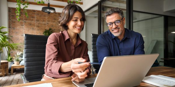 Business,Team,Of,Two,Executives,Working,Together,Using,Laptop,In